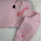 a pair of pink sweatshirts sitting on top of a bed