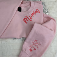 a pair of pink sweatshirts sitting on top of a bed