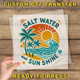 a hand holding a clear plastic sheet with a colorful graphic design of a beach scene, including palm trees, a sun, and waves.