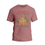 A pink t-shirt with a graphic design featuring a gingerbread house and Christmas decorations, along with text promoting a bakery.