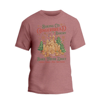 A pink t-shirt with a graphic design featuring a gingerbread house and Christmas decorations, along with text promoting a bakery.