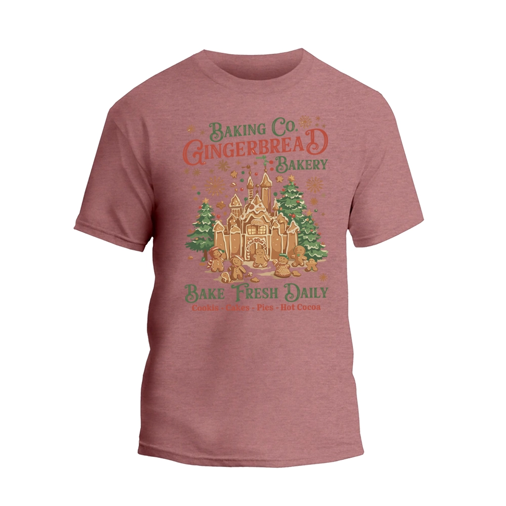 A pink t-shirt with a graphic design featuring a gingerbread house and Christmas decorations, along with text promoting a bakery.