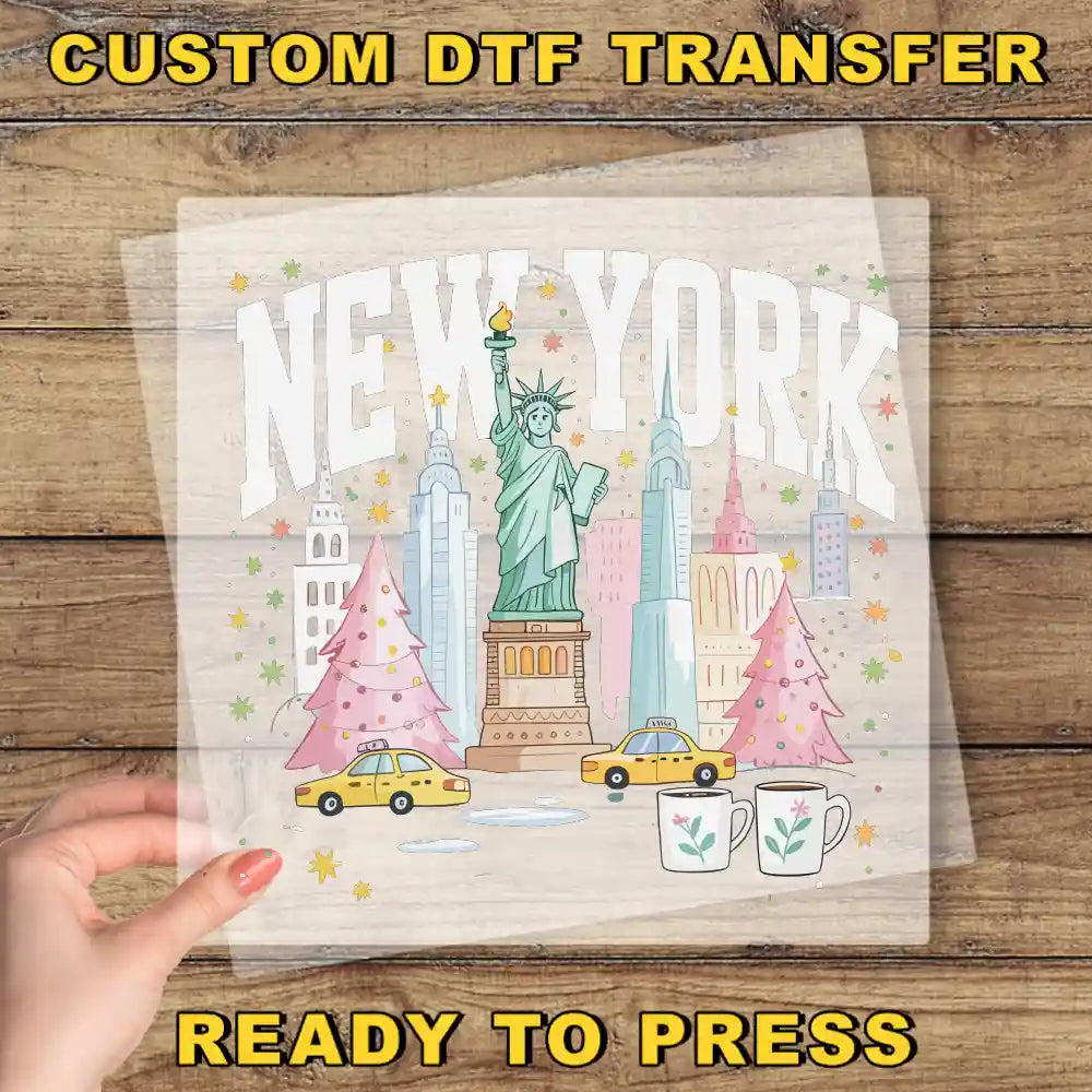 A hand is holding a transparent sheet with a colorful illustration of New York City, including the Statue of Liberty, Christmas trees, and taxis.
