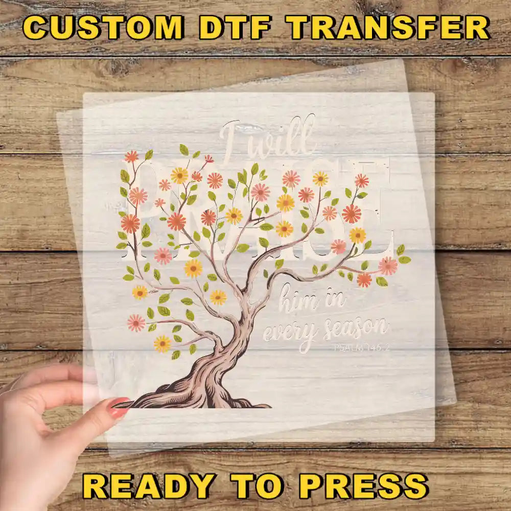 a hand holding a transparent sheet with a tree design and text on it, placed on a wooden surface.