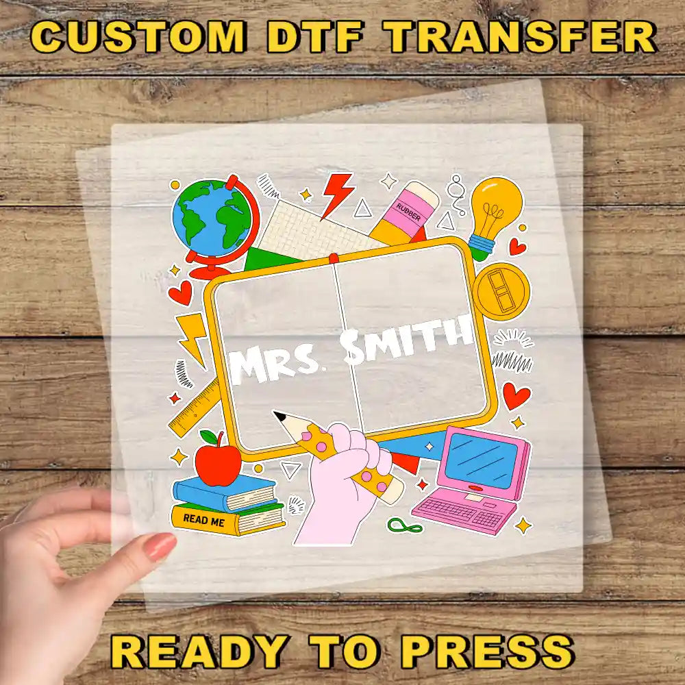 A hand holding a transparent sheet with a colorful illustration of a classroom scene, including a globe, books, a laptop, and various school supplies.