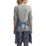 a woman wearing a denim apron and grey shirt