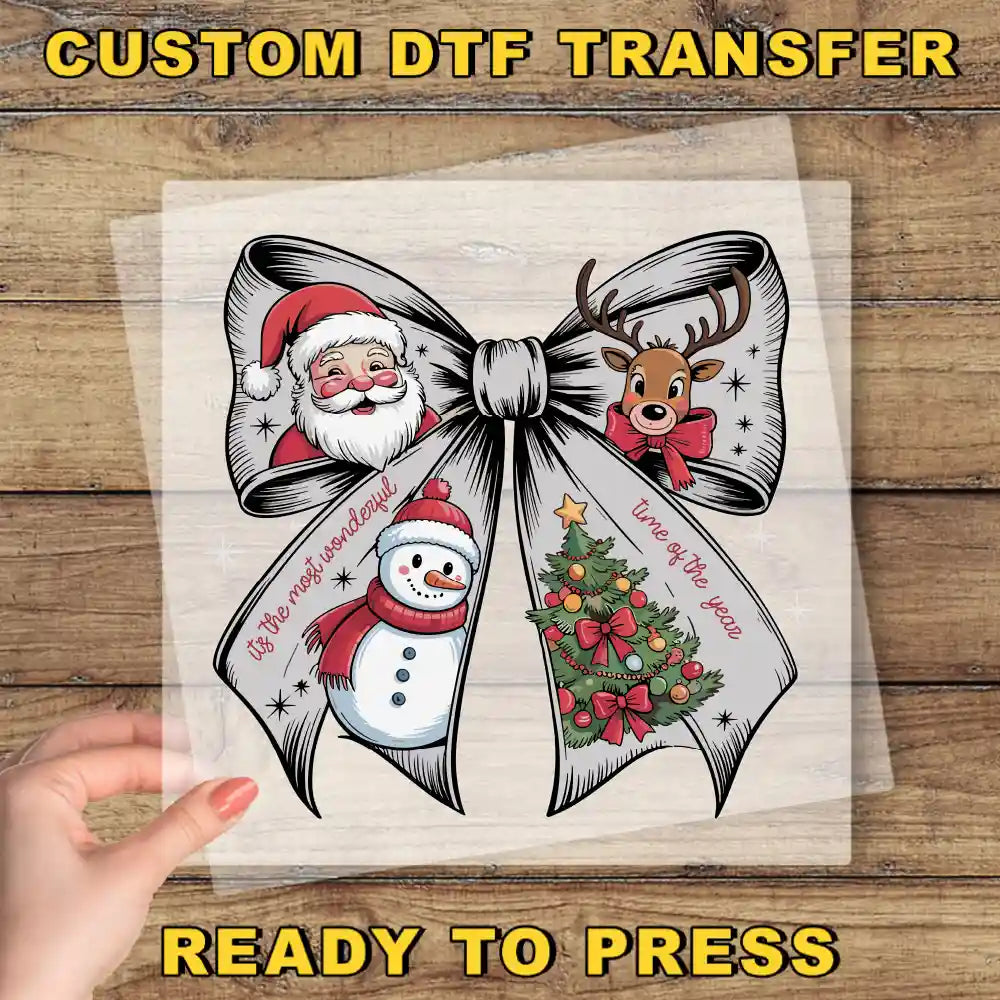 The image is a hand holding a transparent sheet with a large bow featuring illustrations of Santa Claus, a snowman, and a Christmas tree.