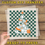 A hand is holding a transparent sheet with a Christmas tree design on it, which is set against a wooden background.