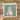 A hand is holding a transparent sheet with a Christmas tree design on it, which is set against a wooden background.