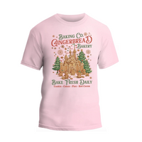 A pink t-shirt with a graphic design featuring a gingerbread house and Christmas decorations, along with text promoting a bakery.