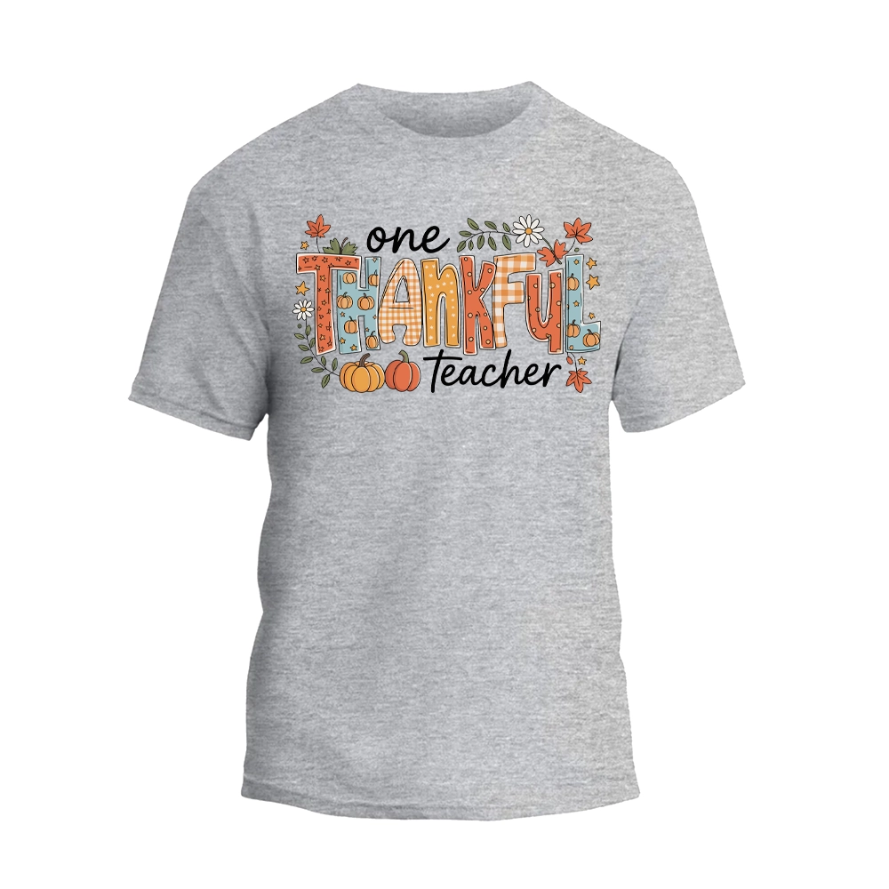 A gray t-shirt with a graphic design featuring the text "One Thankful Teacher" surrounded by autumn-themed elements such as leaves, pumpkins, and flowers.