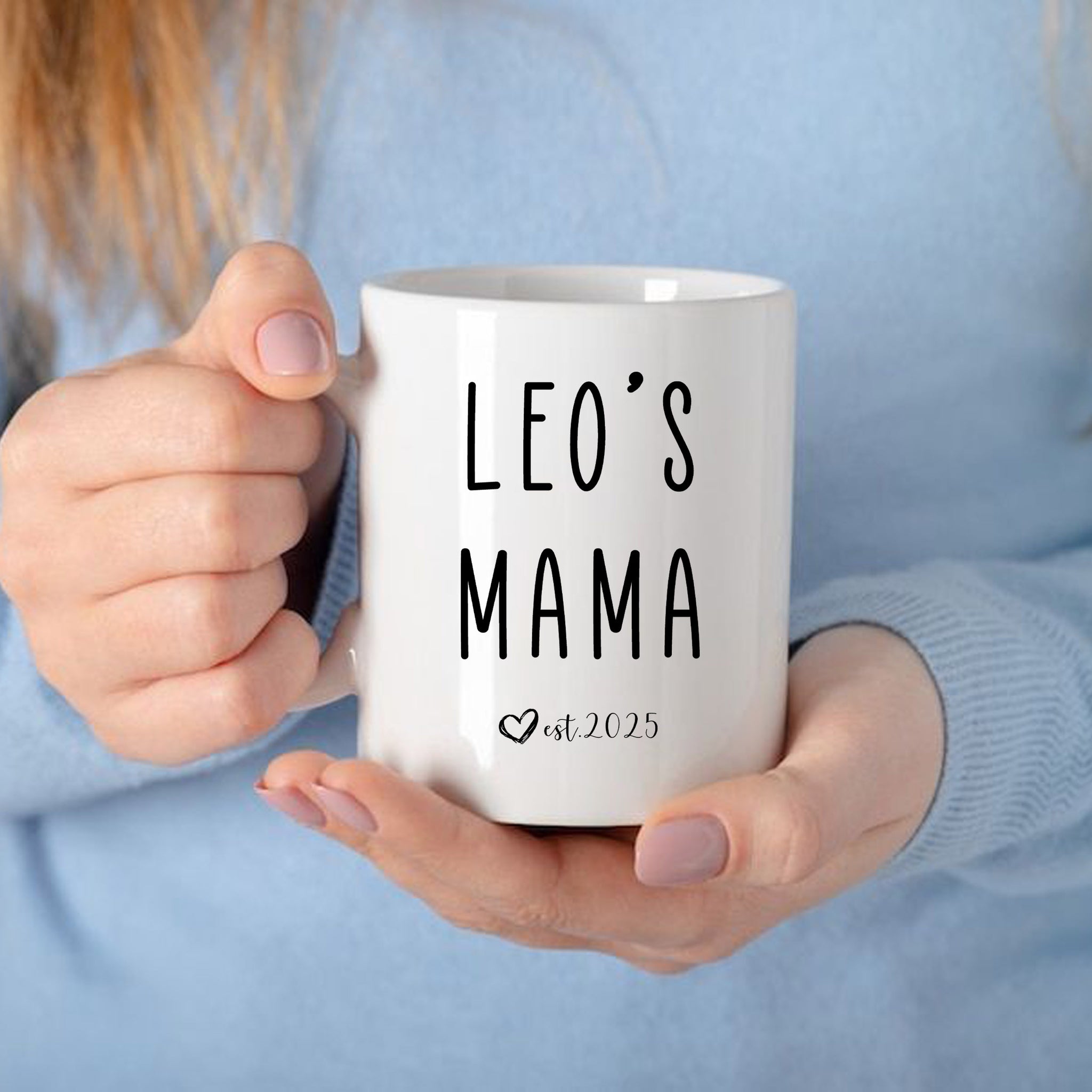 a woman holding a coffee mug that says leo's mama