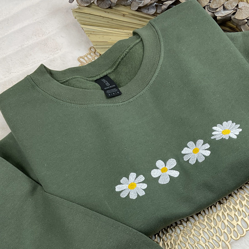 a green sweatshirt with daisies embroidered on it
